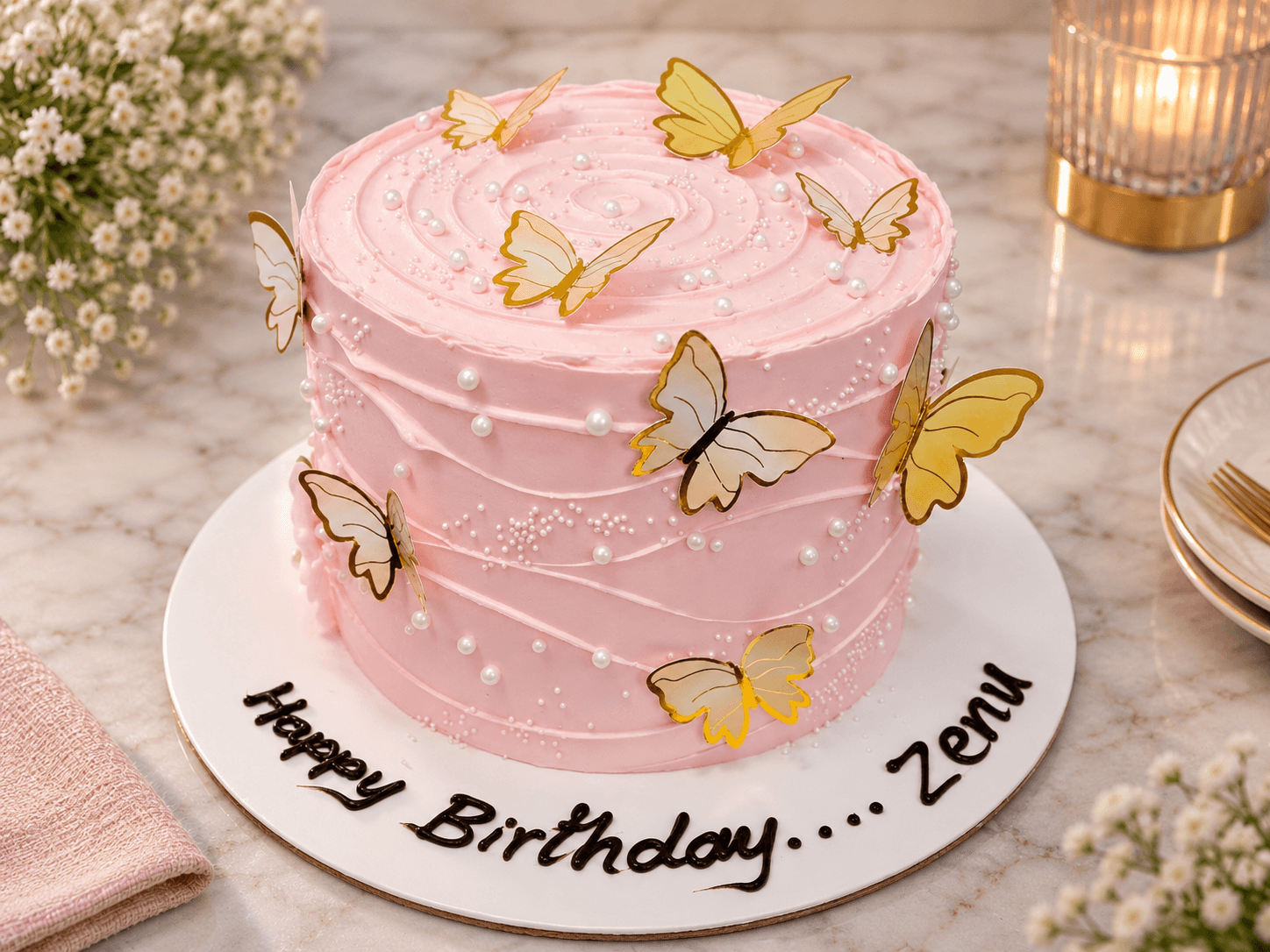 Pink birthday cake with gold butterflies and a hand-piped name